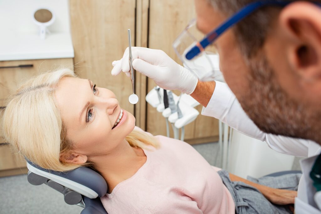 Dentist examines a mature female patient with special dental tools in a modern dental clinic